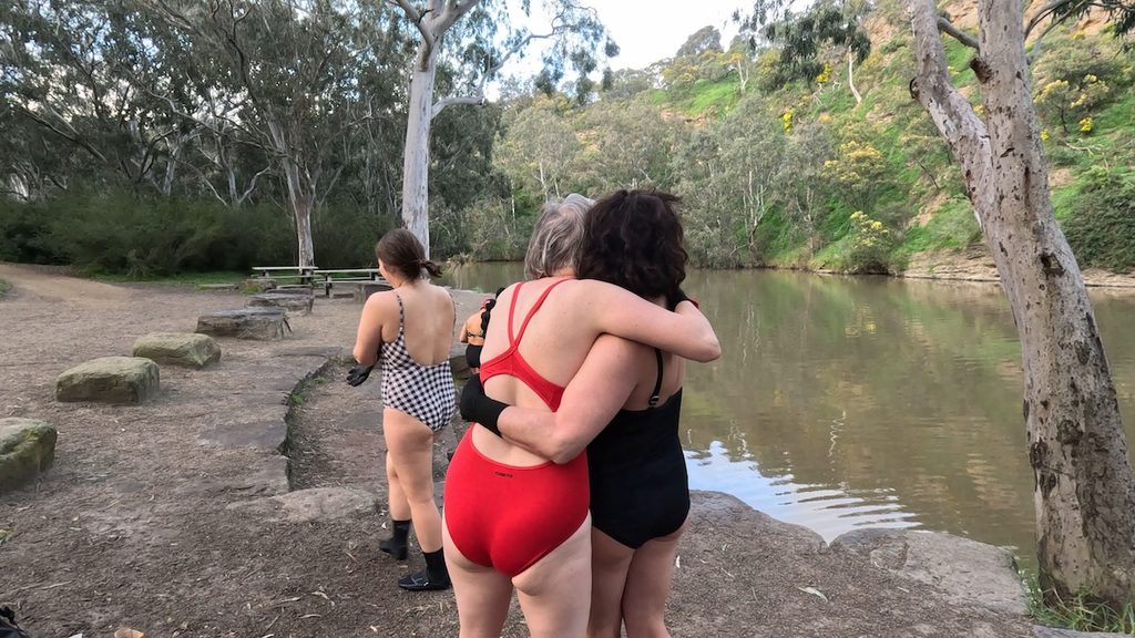 Swimmers hug before getting into the Yarra/Birrarung.